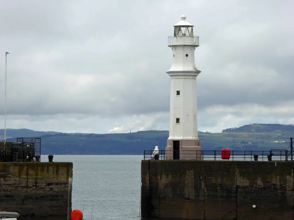 Der weiße Leuchtturm an der Hafenmole von Newhaven, Edinburgh, mit Blick über den Firth of Forth auf die Hügel von Fife.
