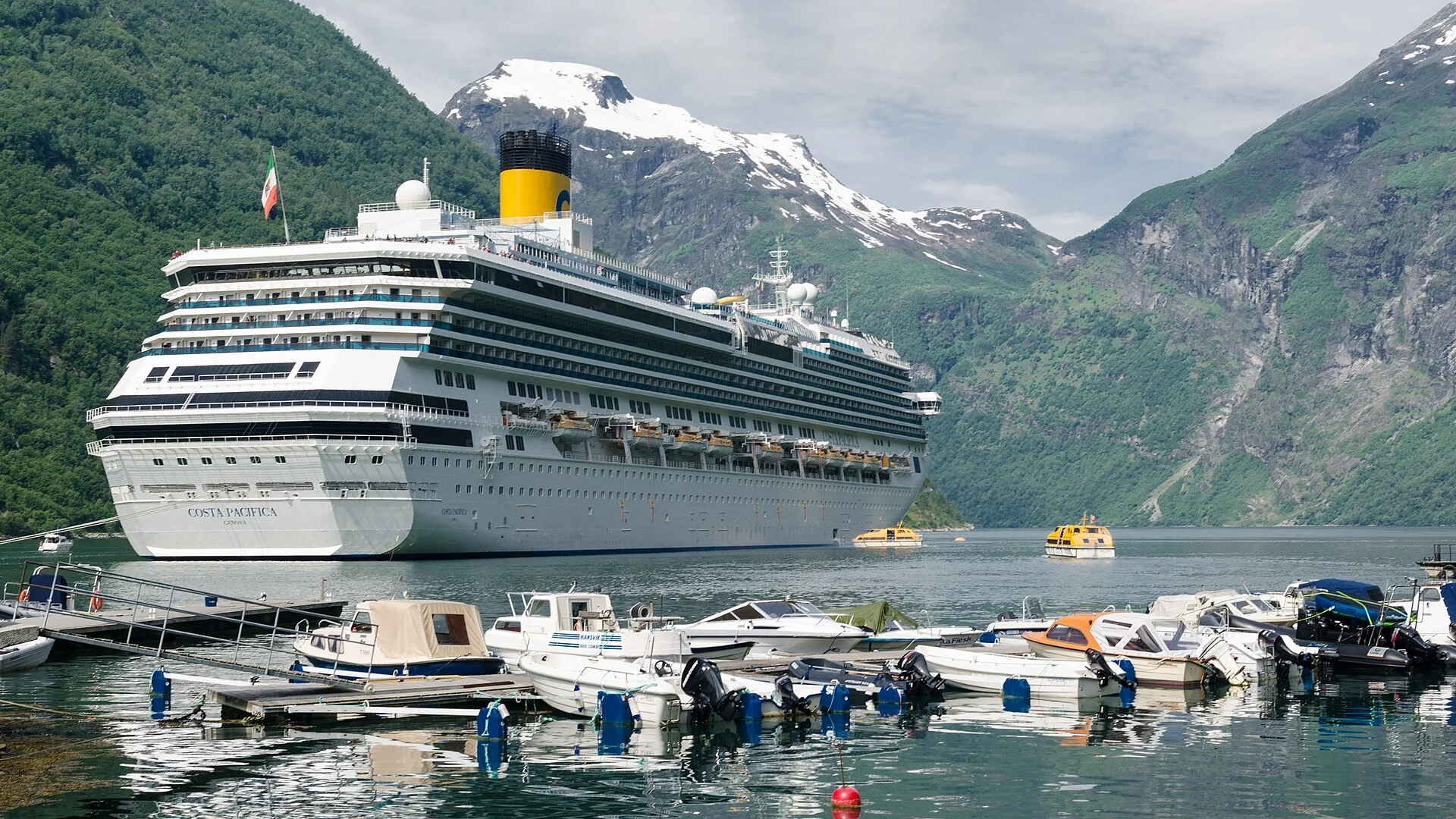 Kreuzfahrtschiff Costa Pacifica auf Reede im Geirangerfjord bei Geiranger, davor Sportboothafen und Tenderboote.