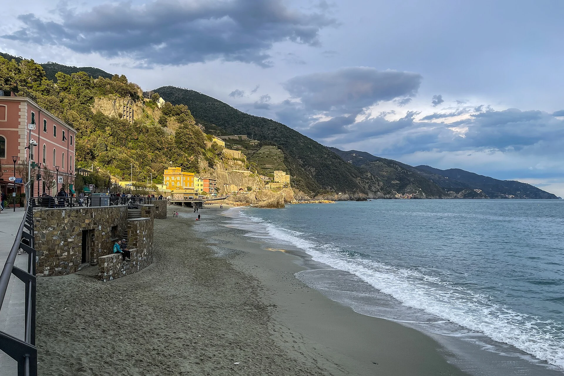 Sandstrand mit Uferpromenade und bewaldeten Küstenbergen in Monterosso al Mare.