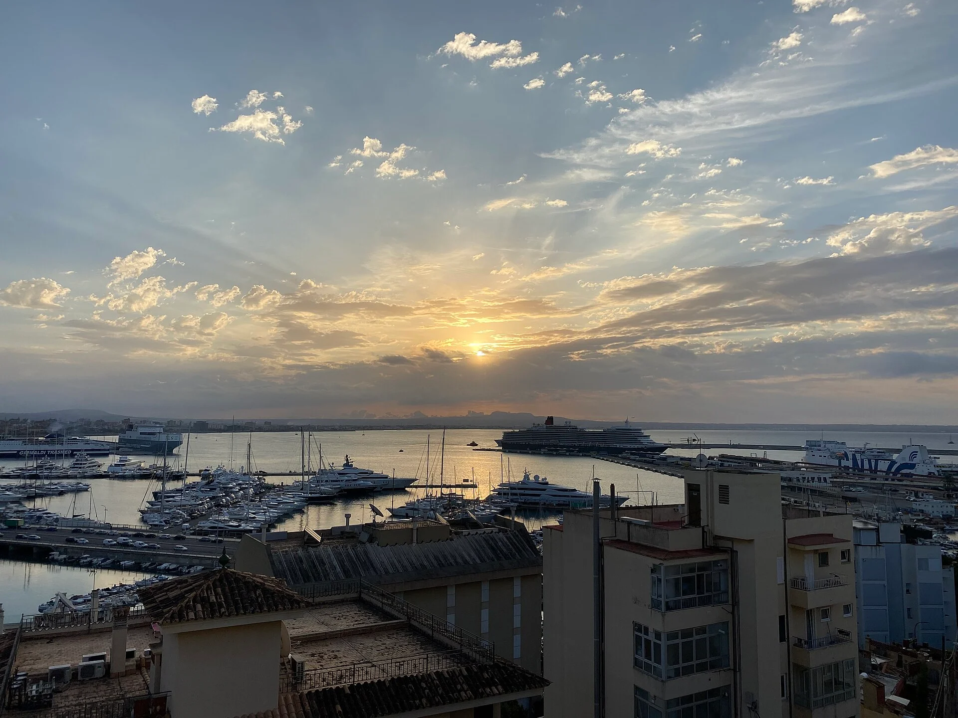 Blick über den Hafen von Palma de Mallorca mit Yachthafen, Fähranleger und einem Kreuzfahrtschiff bei Sonnenaufgang.