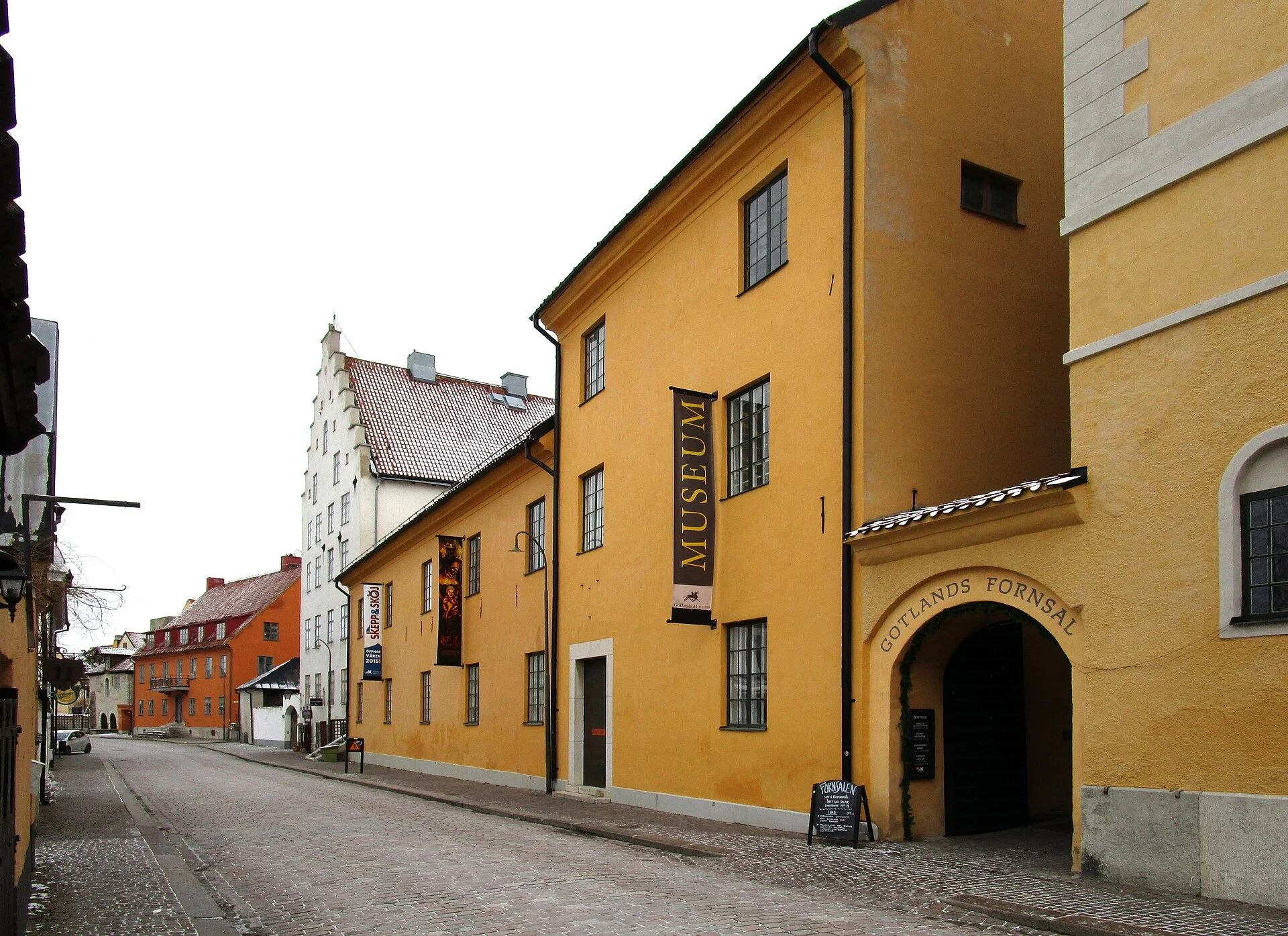 Das gelbe Gebäude des Gotlands Museum mit Banner „Museum“ und Eingangsbogen an der Strandgatan in Visby.