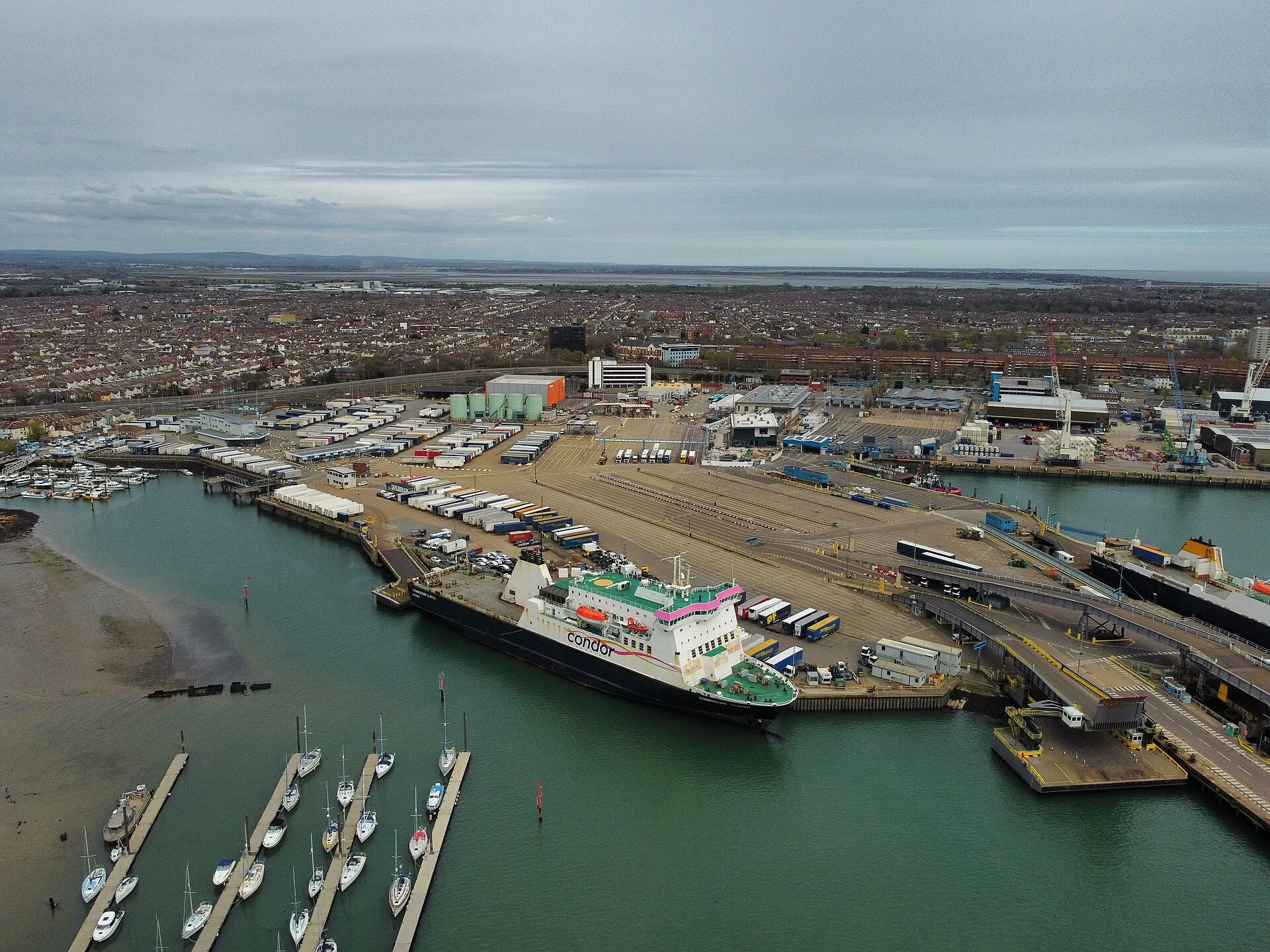 Luftaufnahme des Portsmouth International Port mit längsseits liegendem Fährschiff, Kaianlagen und der Stadt im Hintergrund.