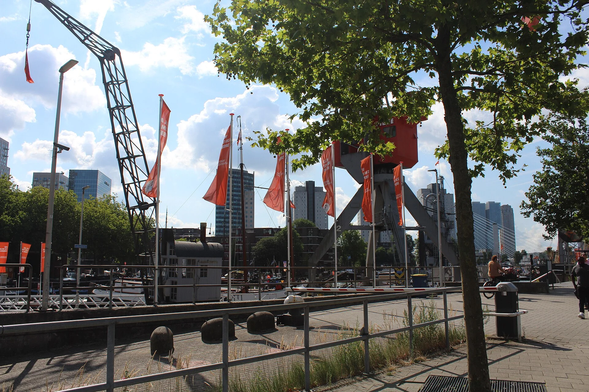 Historische Hafenkräne und Schiffe im Leuvehaven vor der Hochhaus-Skyline von Rotterdam.