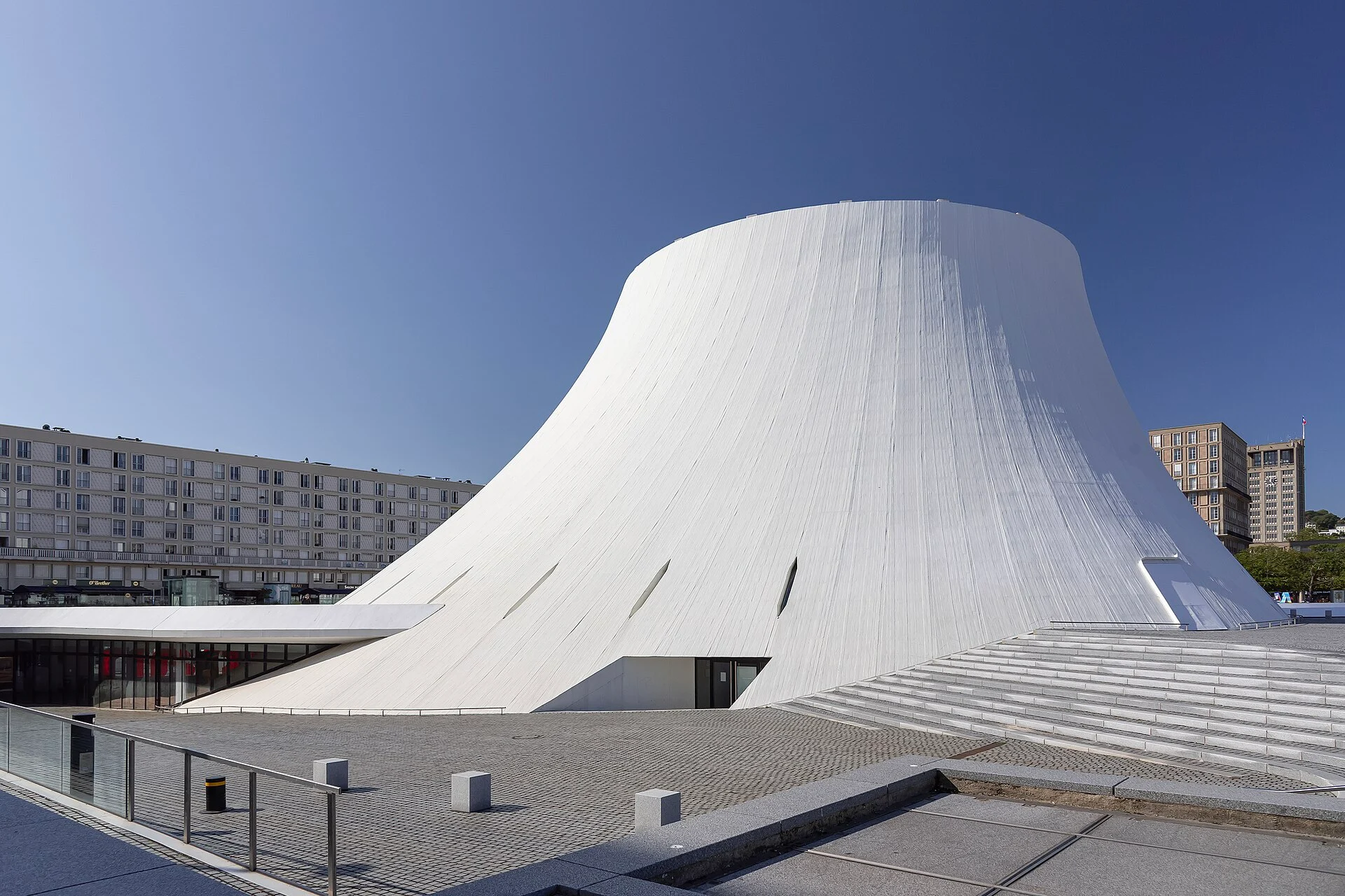 Le Volcan von Oscar Niemeyer in Le Havre mit Freitreppe und Vorplatz vor blauem Himmel.