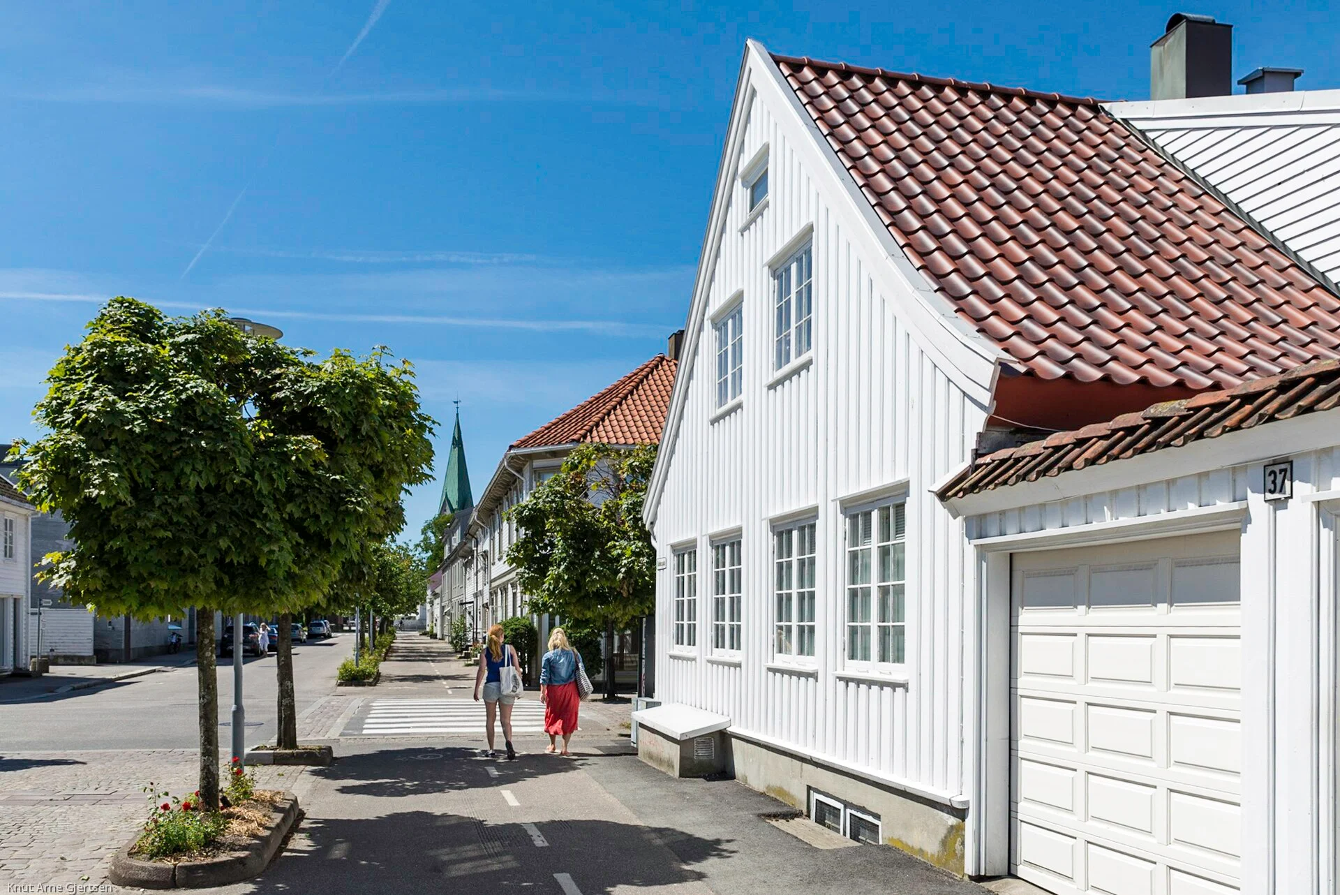 Straße mit niedrigen weißen Holzhäusern und Ziegeldächern in der Posebyen in Kristiansand.