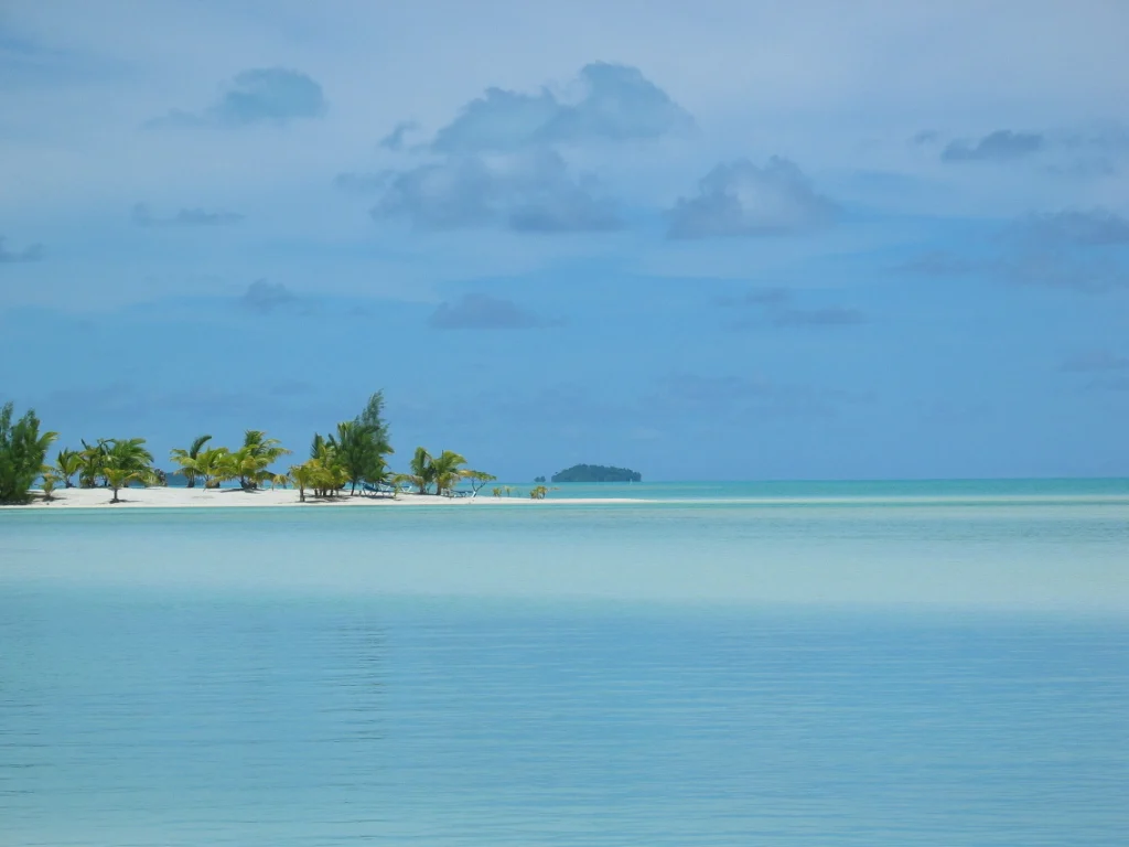 Die türkise Lagune von Aitutaki mit einem Motu am Riffrand