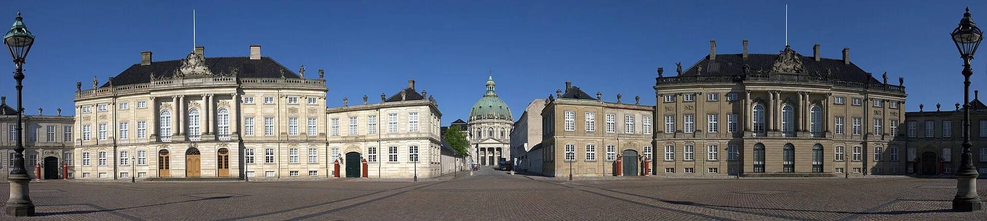 Panorama des Schlossplatzes Amalienborg in Kopenhagen mit zwei Palais und der Kuppel der Marmorkirche im Hintergrund.
