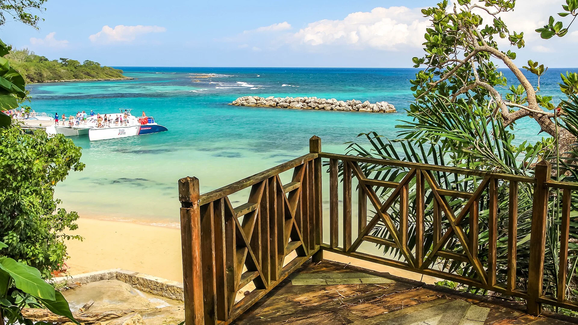 Der Strand am Fuß der Dunn’s River Falls bei Ocho Rios mit türkisem Wasser und Ausflugsbooten