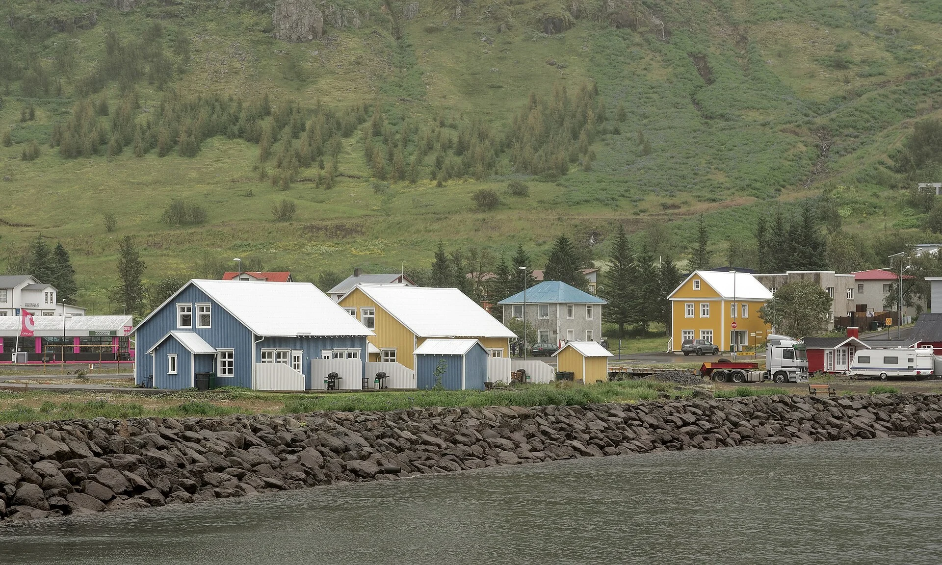 Bunte Holzhäuser in Seyðisfjörður vor der Fjordwand