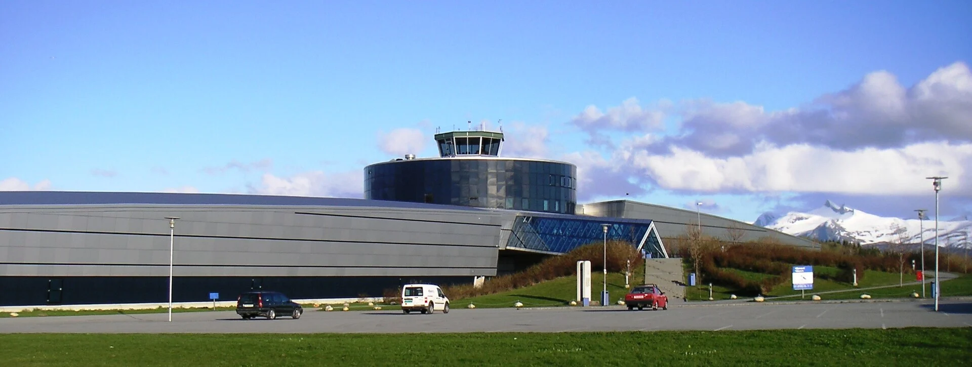 Außenansicht des Norwegischen Luftfahrtmuseums in Bodø mit charakteristischem Tower-Aufbau und verschneiten Bergen im Hintergrund.