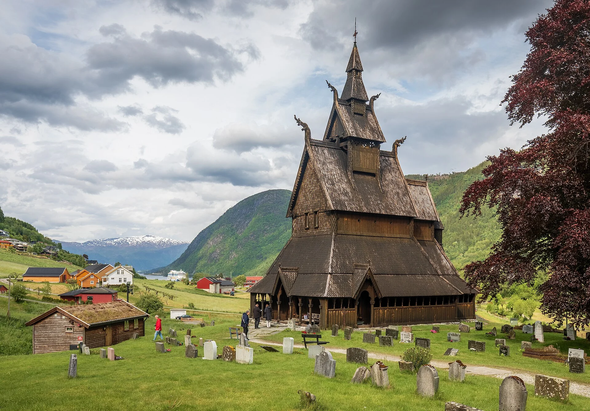 Die Stabkirche Hopperstad bei Vik mit Friedhof und Fjordlandschaft