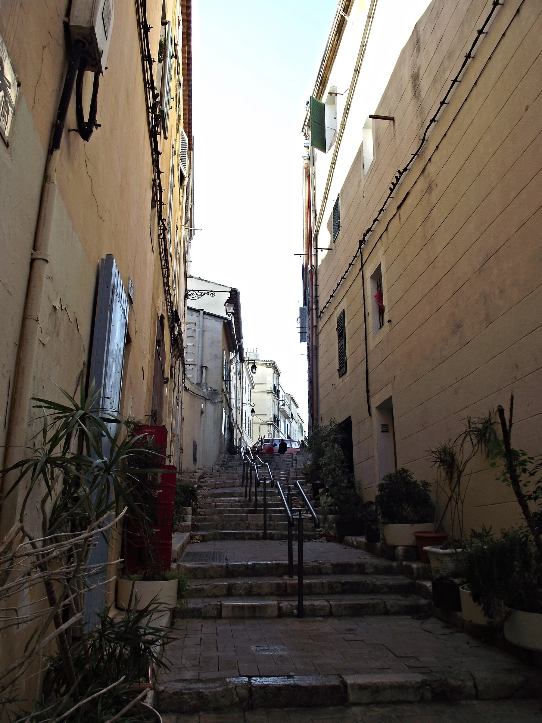 Enge Treppengasse Rue des Moulins im Viertel Le Panier in Marseille, gesäumt von Altbaufassaden und Pflanzkübeln.
