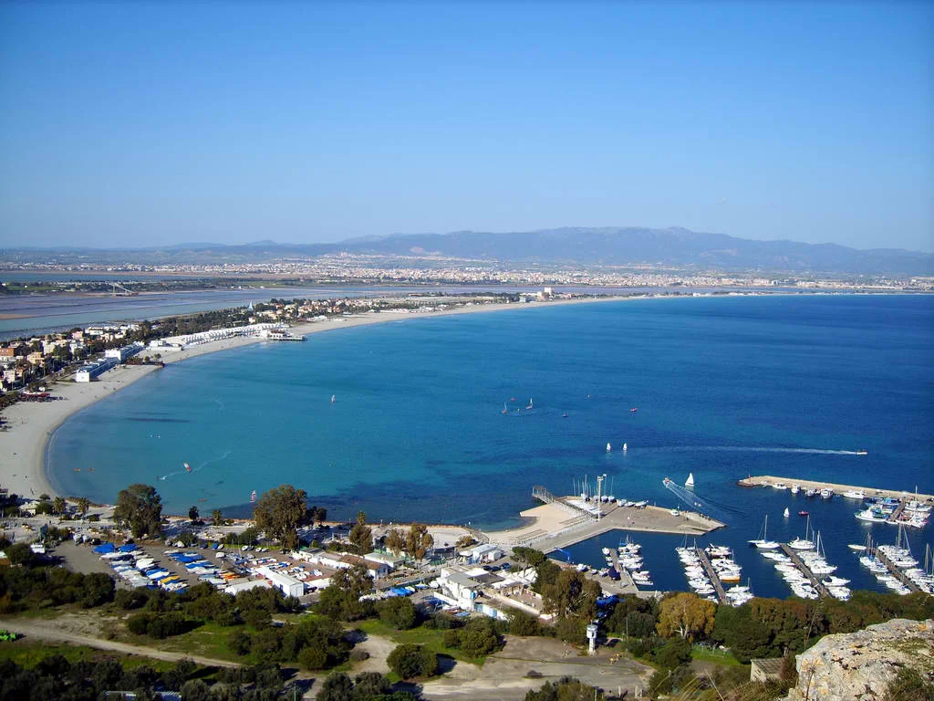 Die Bucht des Poetto bei Cagliari mit dem langen Sandstrand, dem Hafen und der Stadt im Hintergrund