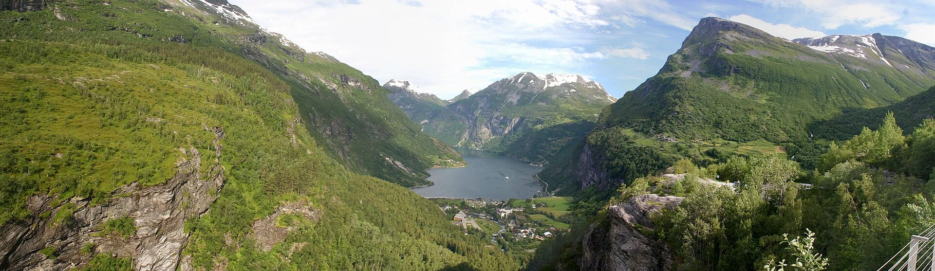 Panoramablick vom Aussichtspunkt Flydalsjuvet über Geiranger und den Geirangerfjord mit der vorspringenden Felsnase rechts im Bild.