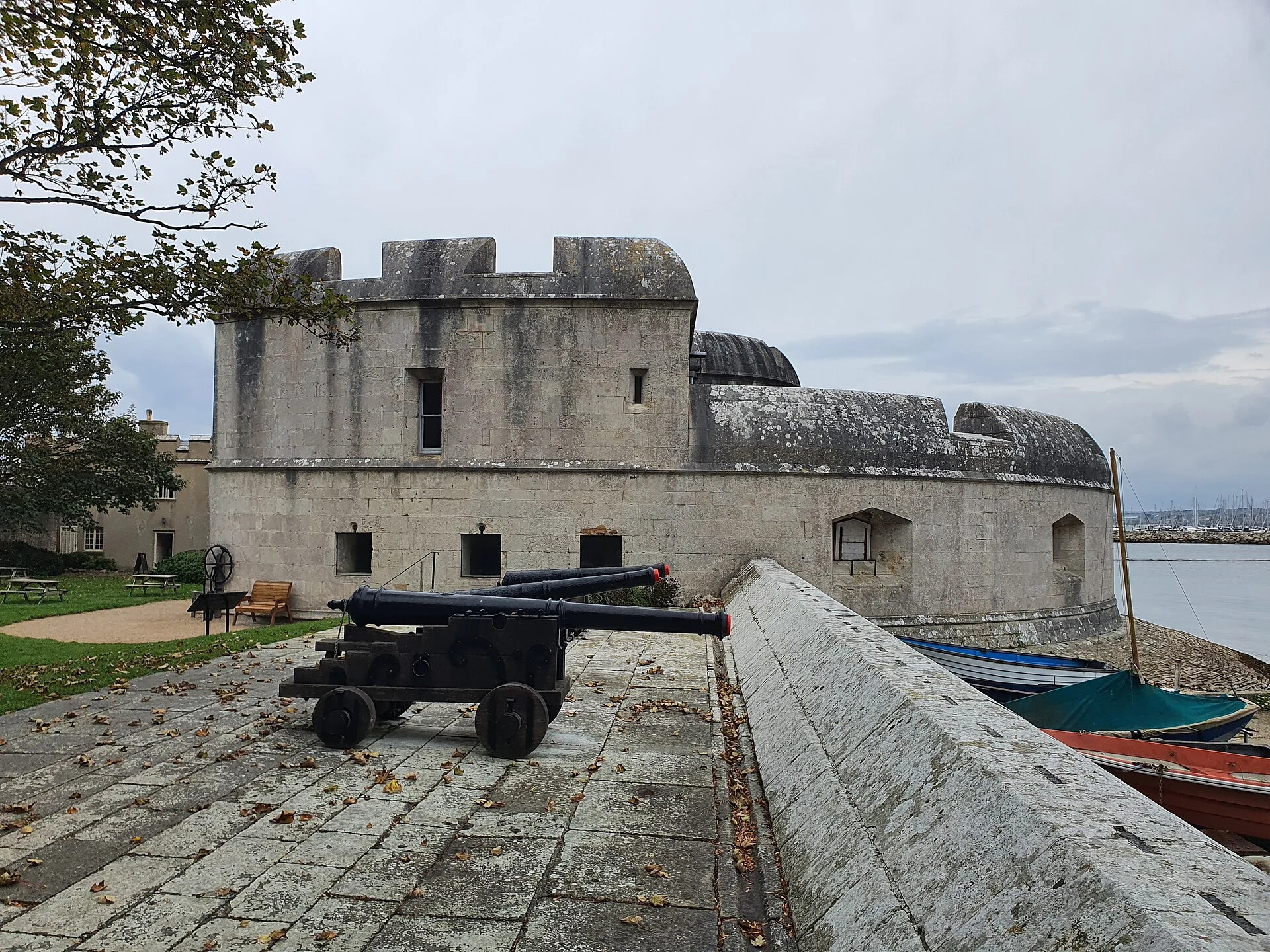 Der halbrunde Steinbau von Portland Castle in Castletown mit historischen Kanonen im Vordergrund und Blick auf den Hafen.