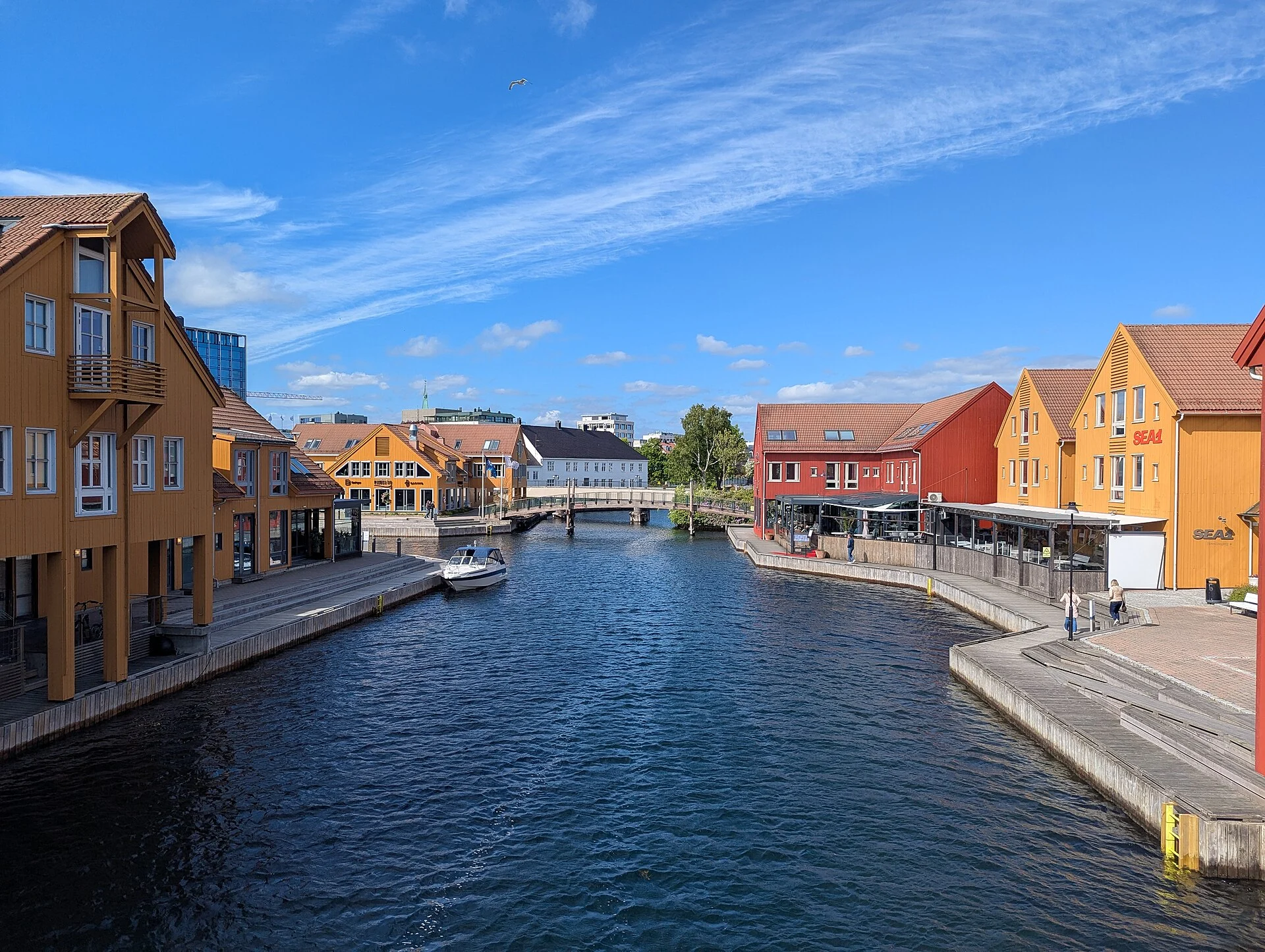 Blick über den Kanal Gravane an der Fiskebrygga in Kristiansand mit gelben und roten Holzhäusern und der Fußgängerbrücke.