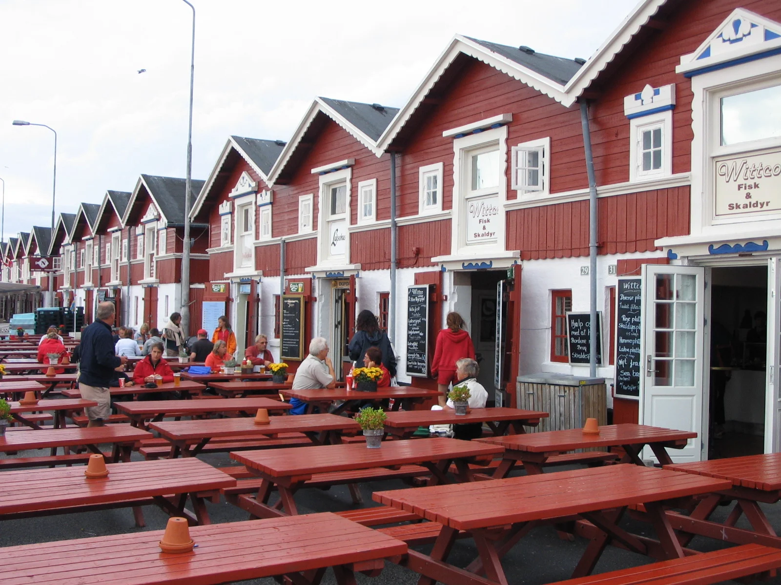 Die roten Hafenbuden mit Fischrestaurants und Bänken im Hafen von Skagen