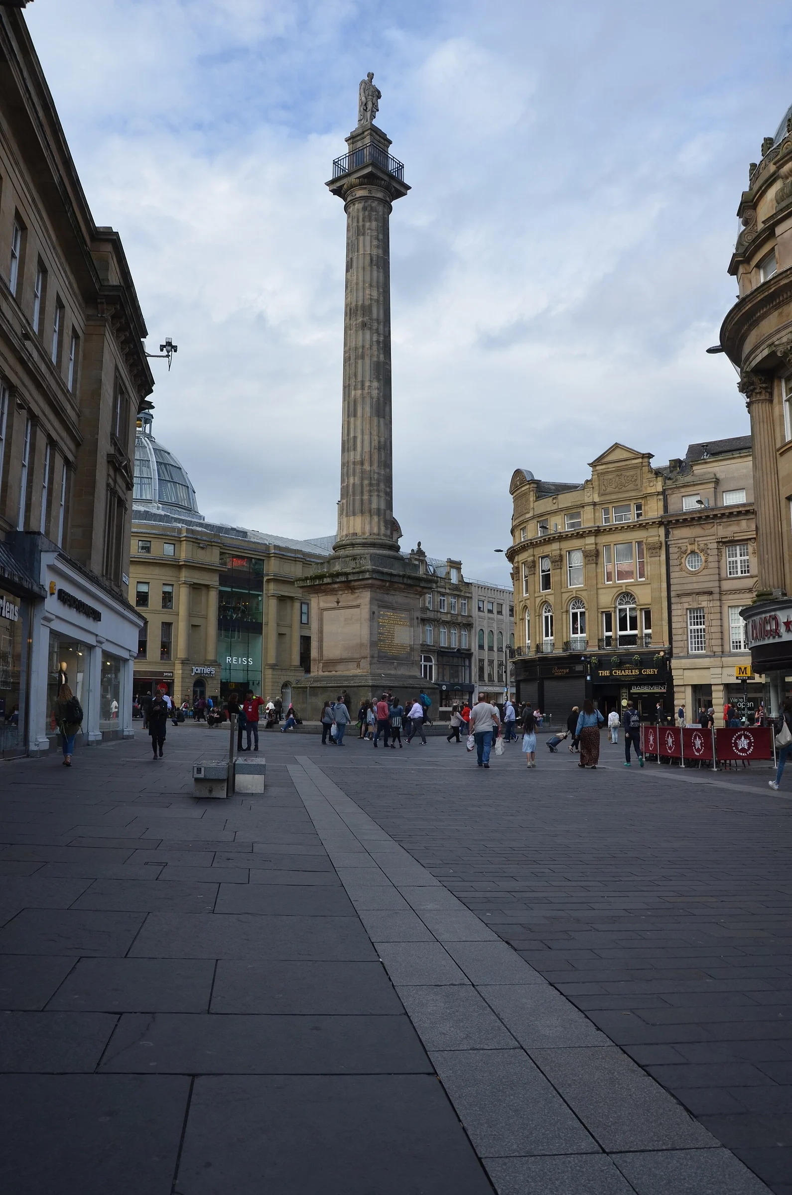 Grey's Monument mit Säule und Earl-Grey-Statue auf dem Platz in Grainger Town, Newcastle upon Tyne, umgeben von klassizistischen Geschäftshäusern.