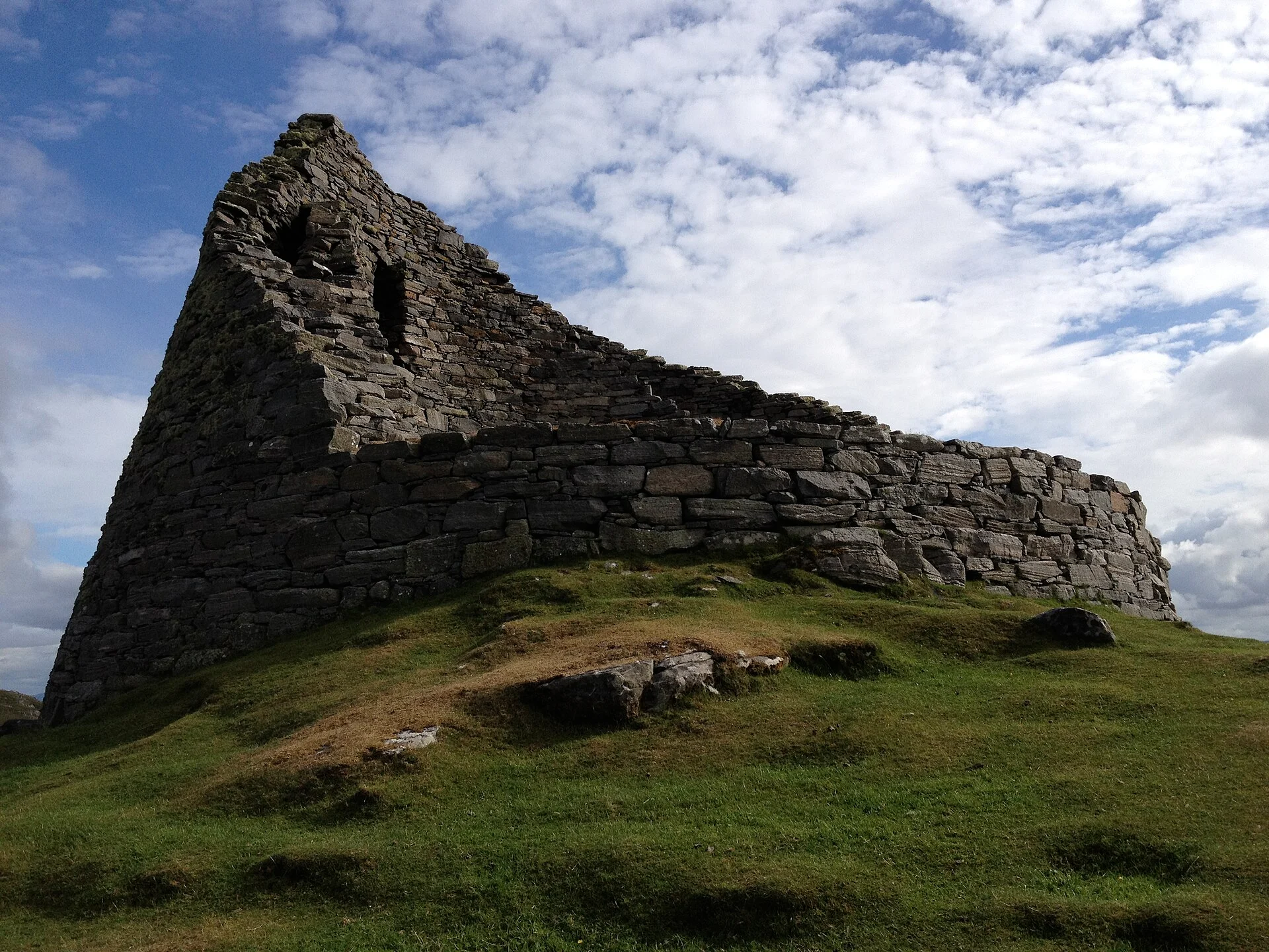 Die charakteristische, bis neun Meter hohe Mauersichel des Dun Carloway Broch auf grünem Hügel, Isle of Lewis.