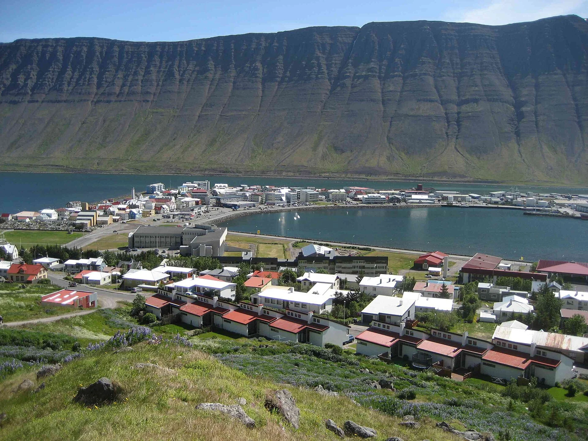 Ísafjörður auf seiner Sandbank im Skutulsfjörður, dahinter die steile Bergwand