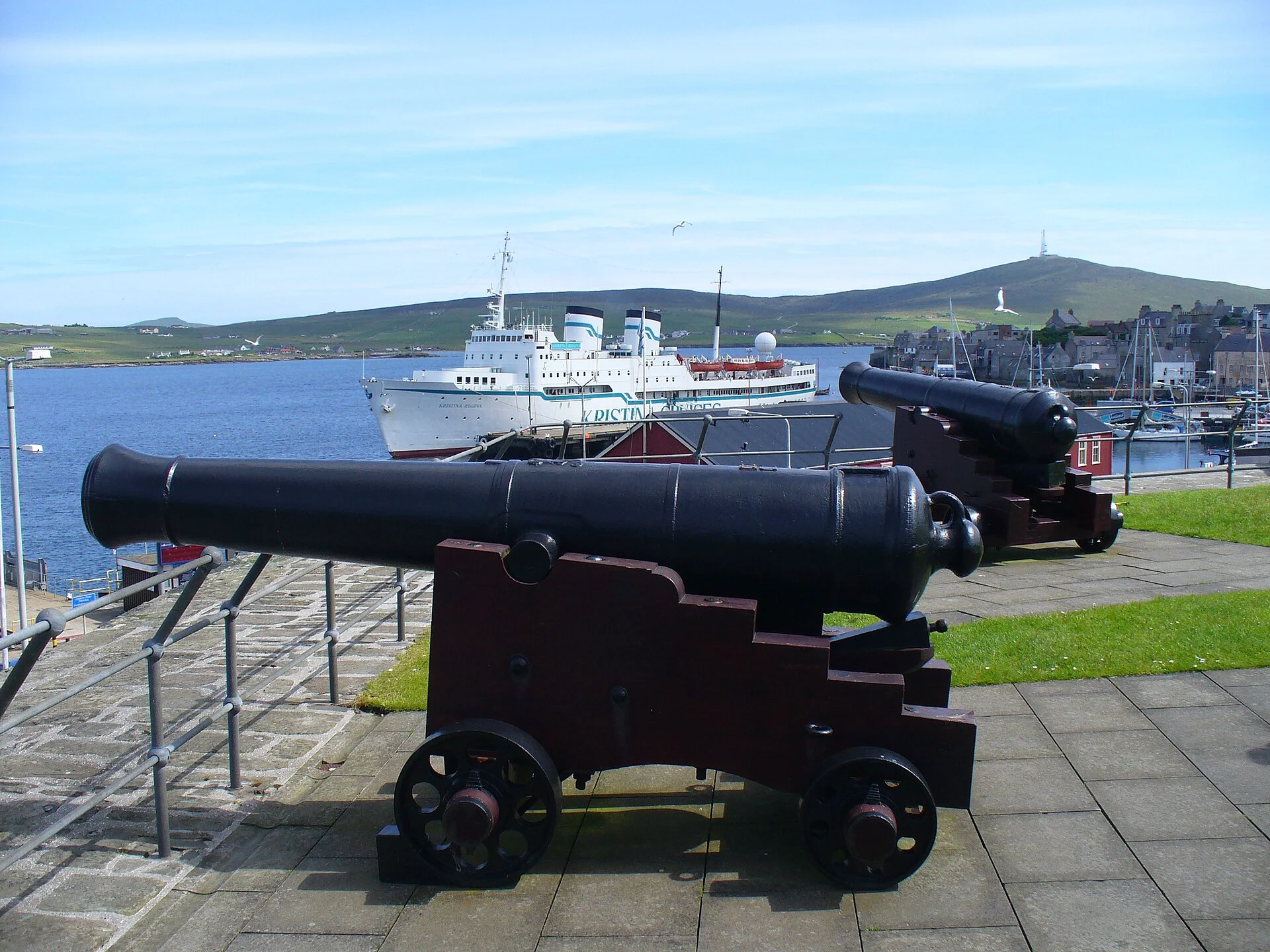 Historische Kanonen auf der Bastion von Fort Charlotte in Lerwick mit Blick über den Hafen und ein Schiff auf dem Bressay Sound.