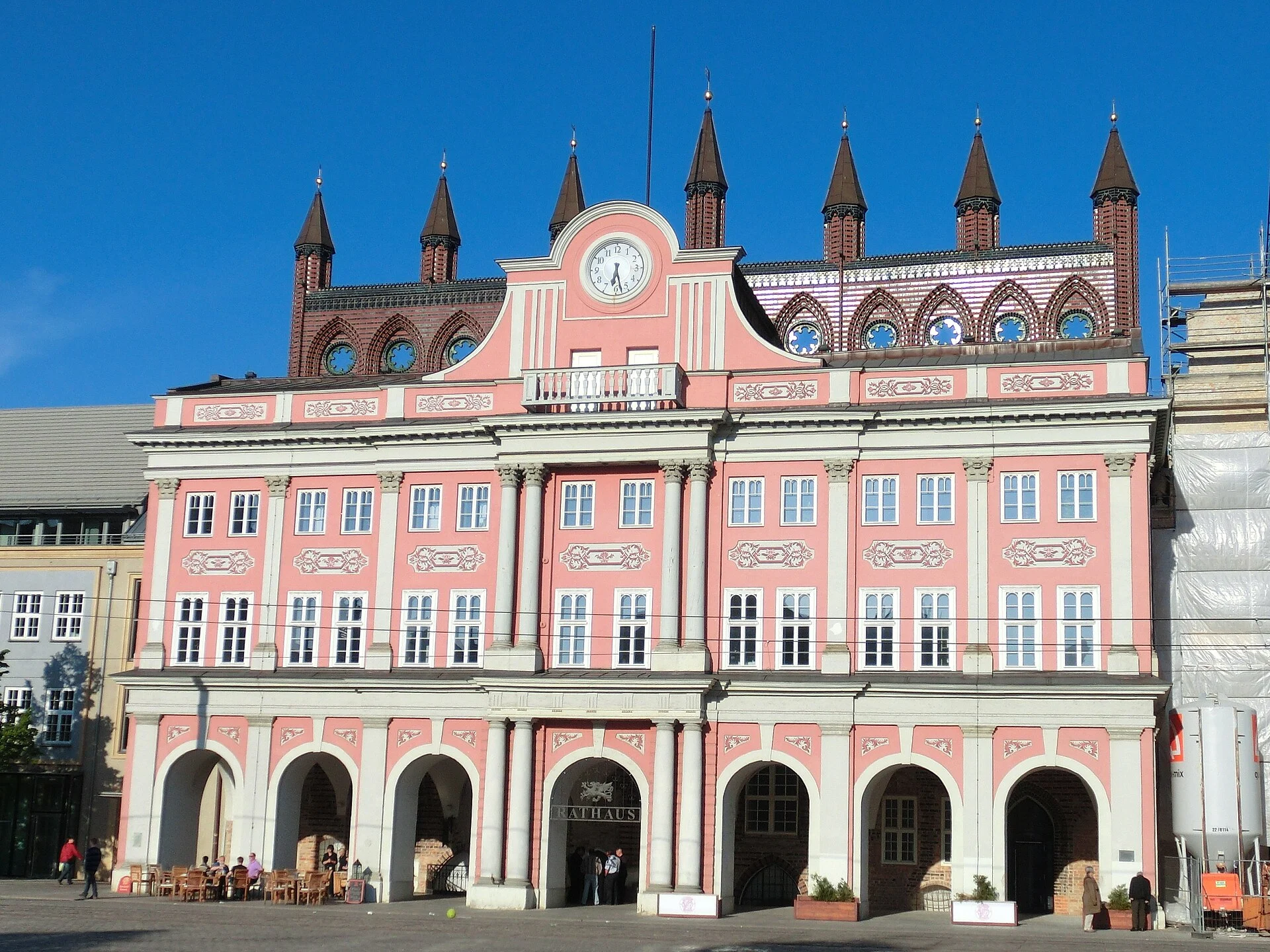Das rosafarbene Rathaus am Neuen Markt in der Rostocker Altstadt mit barocker Vorderfront und gotischen Türmchen.