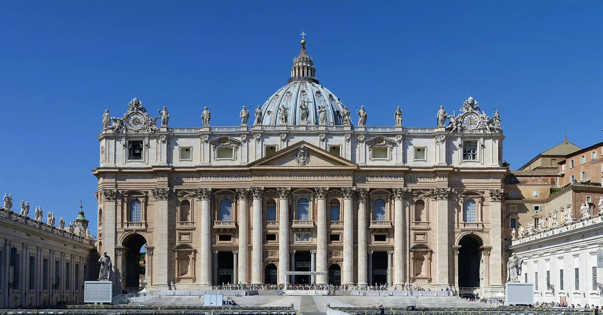 Ostfassade des Petersdoms im Vatikan mit Michelangelos Kuppel bei blauem Himmel.