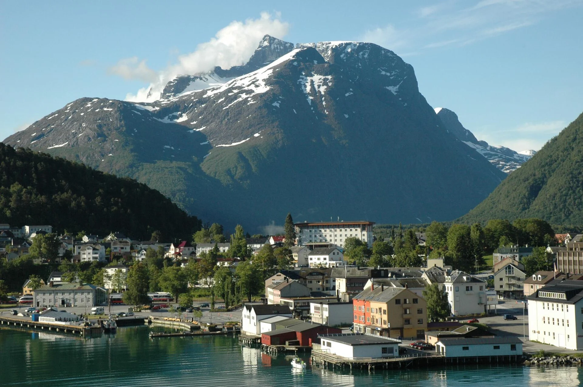 Åndalsnes vom Fjord aus gesehen, mit Ortszentrum, Kai und dem steilen Bergmassiv des Romsdals im Hintergrund.