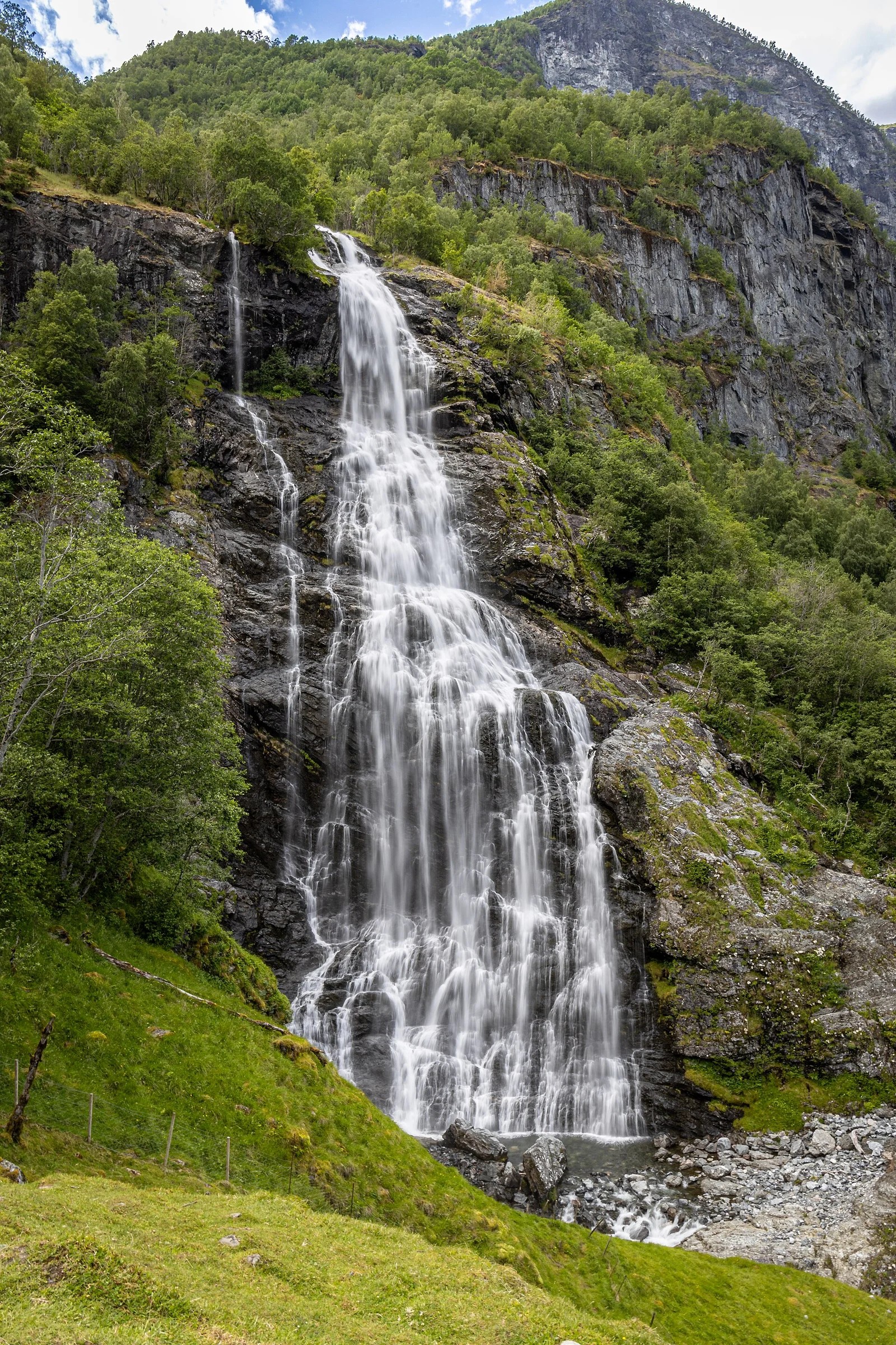 Frontalansicht des Wasserfalls Brekkefossen bei Flåm mit Felswand und Birkenhang.