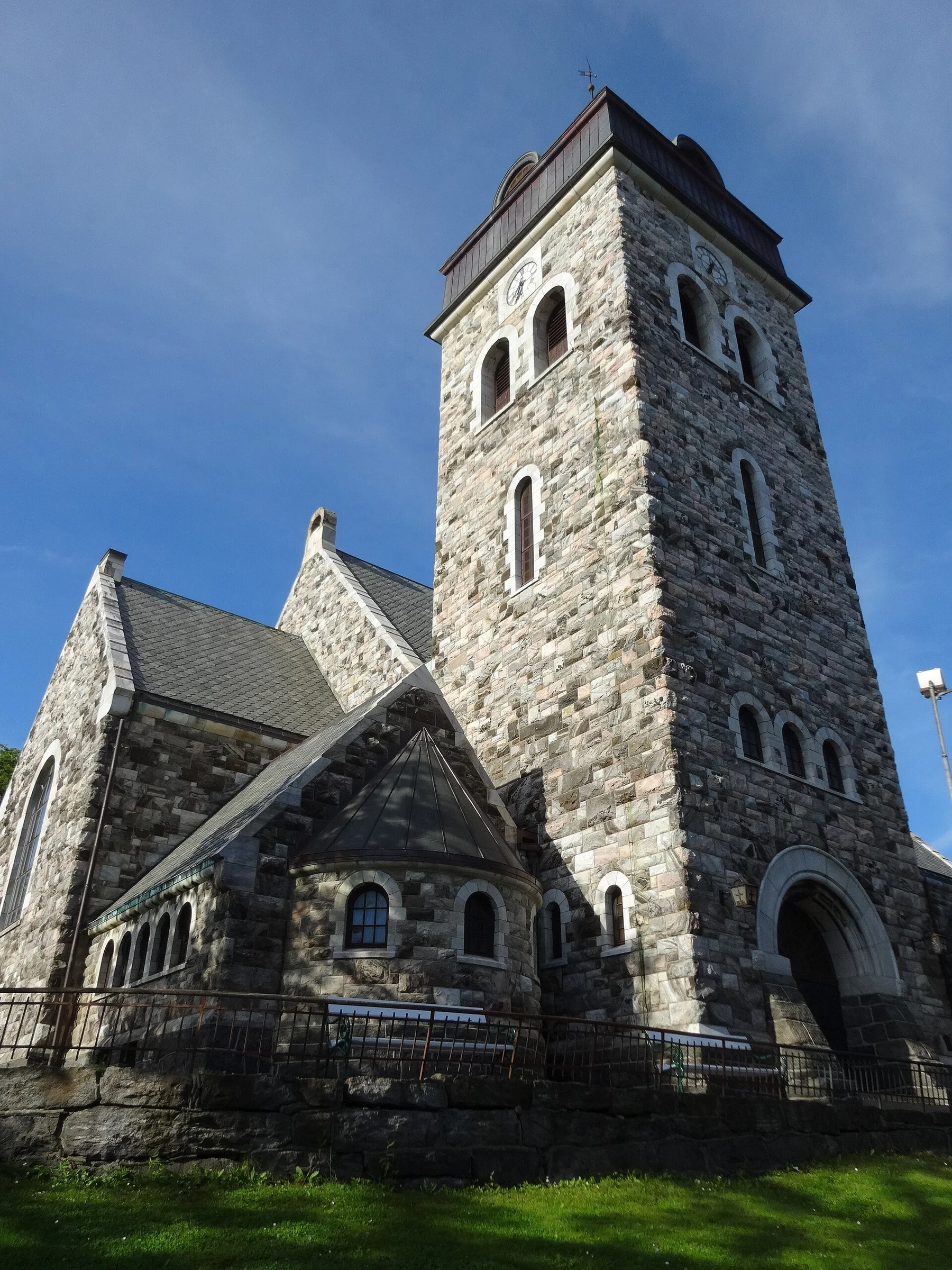 Außenansicht der Ålesund kirke in Ålesund, Norwegen, mit wuchtigem Steinturm und Portal.