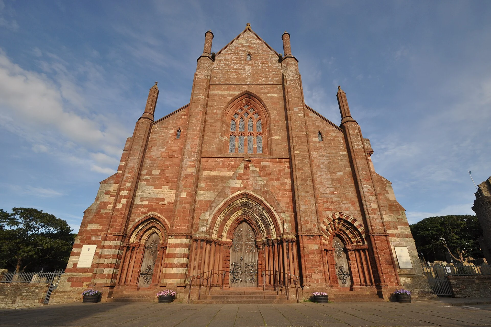 Westfassade der St Magnus Cathedral in Kirkwall aus rotem und gelbem Sandstein mit den drei Portalen.