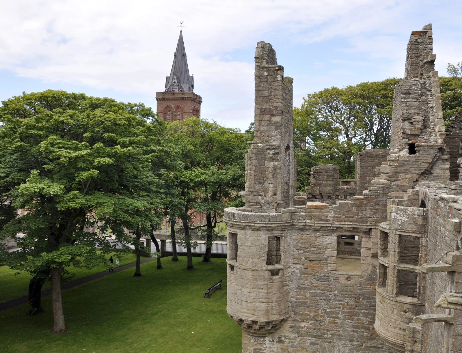 Mauerreste und Erkertürmchen des Earl's Palace in Kirkwall mit dem Turm der St.-Magnus-Kathedrale im Hintergrund.