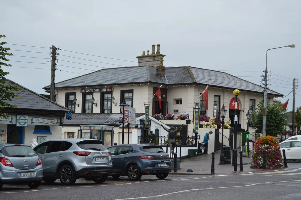 Das ehemalige Abfertigungsgebäude der White Star Line am Casement Square in Cobh, heute Titanic Experience, mit Schriftzug und Flaggen.