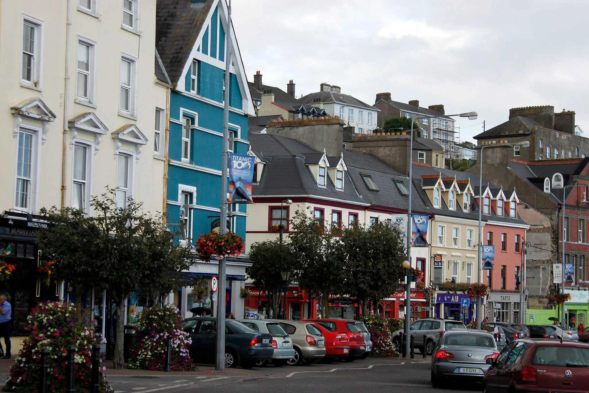 Bunte Häuserzeile an der Uferstraße von Cobh mit ansteigendem Ortsbild im Hintergrund, Irland.
