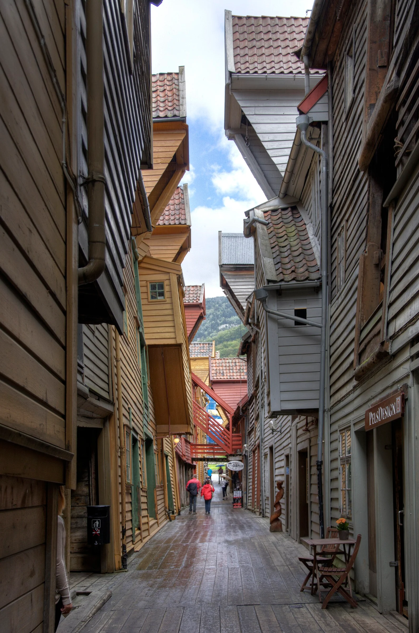 Schmale Holzgasse zwischen den bunten Giebelhäusern der Bryggen in Bergen mit hölzernem Bohlenweg.