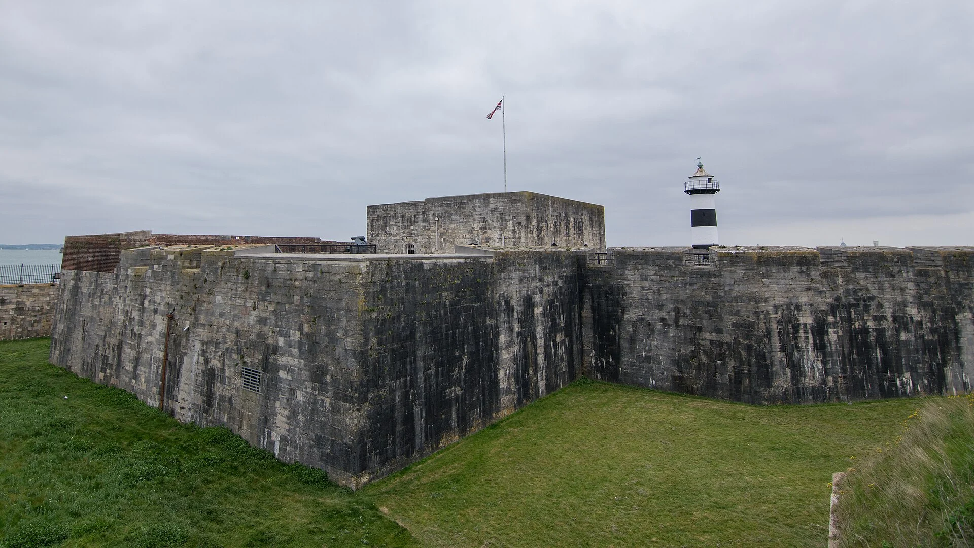 Die gedrungenen Steinwälle und der zentrale Keep von Southsea Castle in Portsmouth, rechts der schwarz-weiße Leuchtturm.