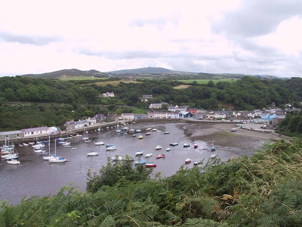 Blick über den Naturhafen von Lower Fishguard mit Segelbooten bei Ebbe und der Häuserzeile am Kai, Pembrokeshire, Wales.