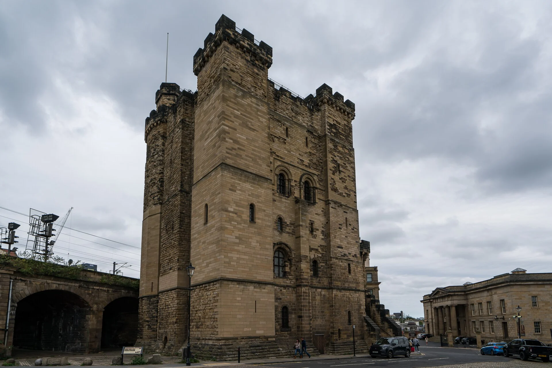 Der normannische Castle Keep in Newcastle upon Tyne, aufragender Sandsteinbergfried mit Zinnen, daneben Bahnviadukt und Straßenzug.