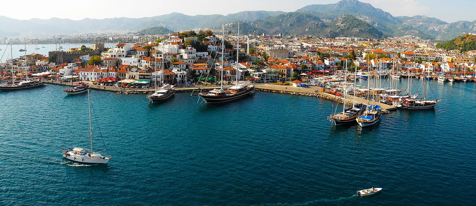 Die Bucht von Marmaris mit Booten am Kai, dahinter der Ort und bewaldete Berge