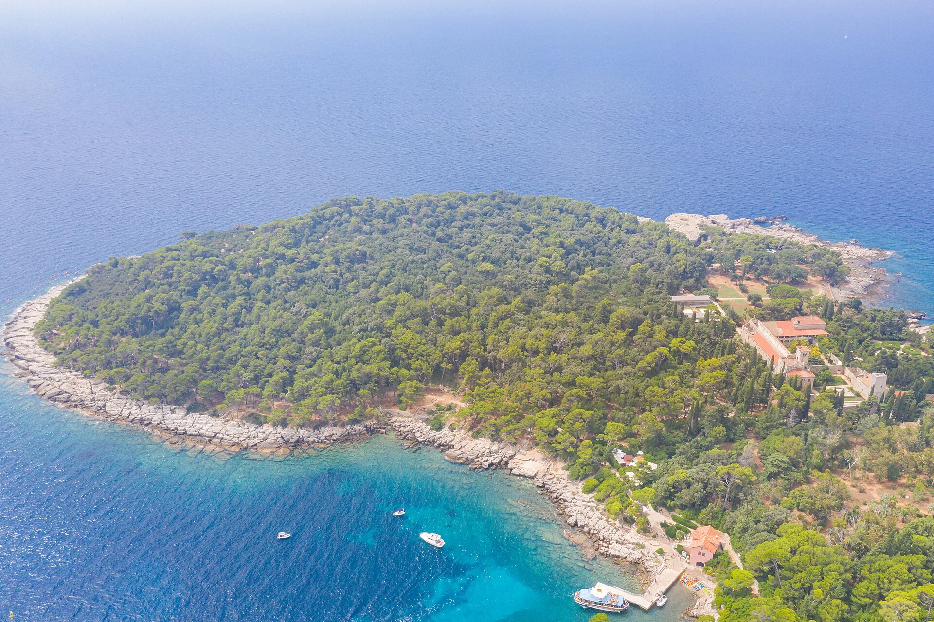 Luftbild der bewaldeten Insel Lokrum vor Dubrovnik mit Hafenanleger und dem Benediktinerkloster St. Maria.
