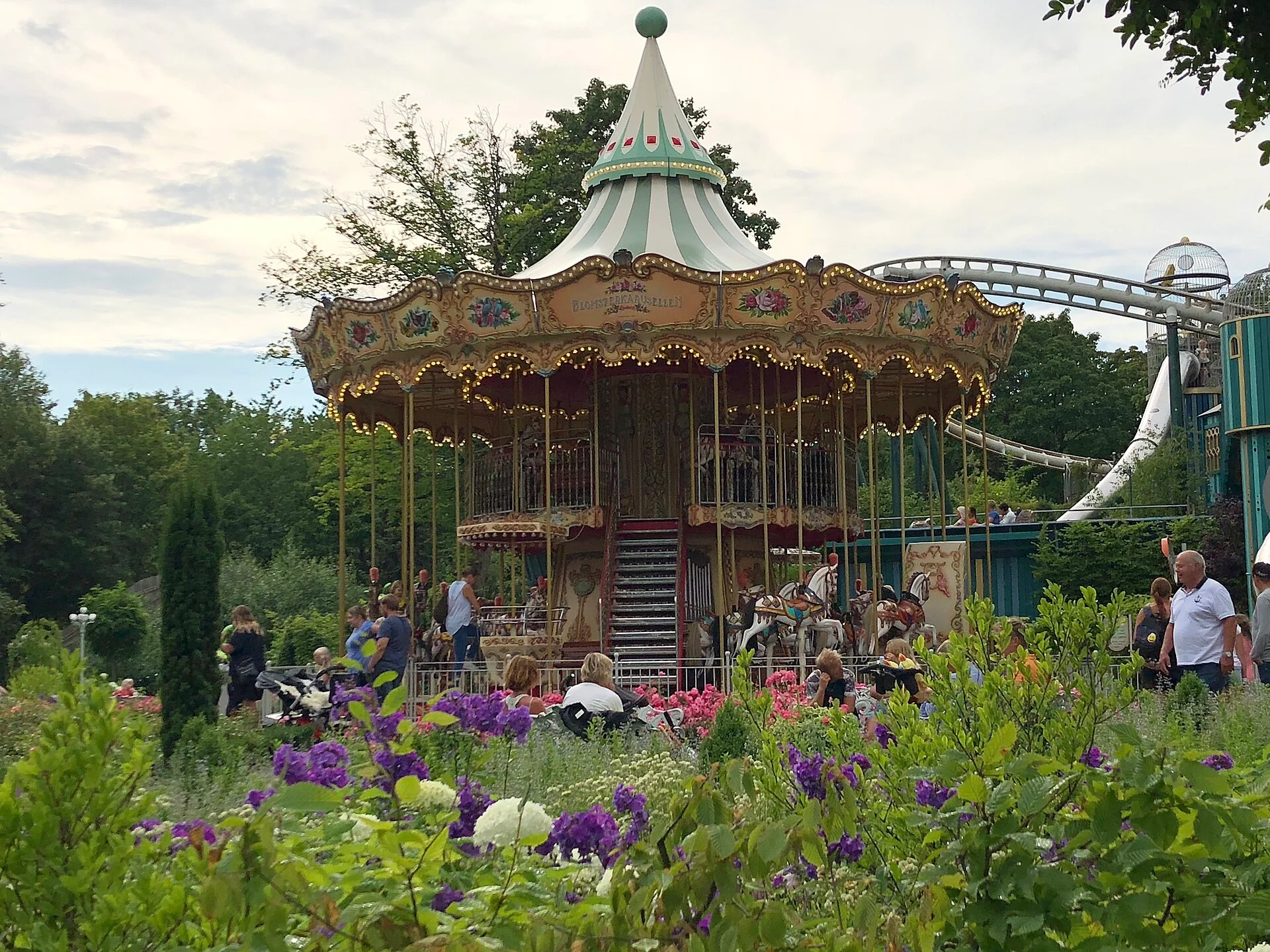 Historisches Karussell zwischen Blumenbeeten im Vergnügungspark Liseberg in Göteborg