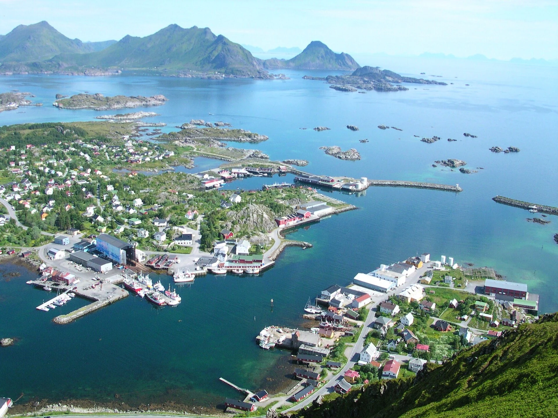 Der Fischereihafen von Ballstad auf den Lofoten mit Booten, Hallen und vorgelagerten Inseln