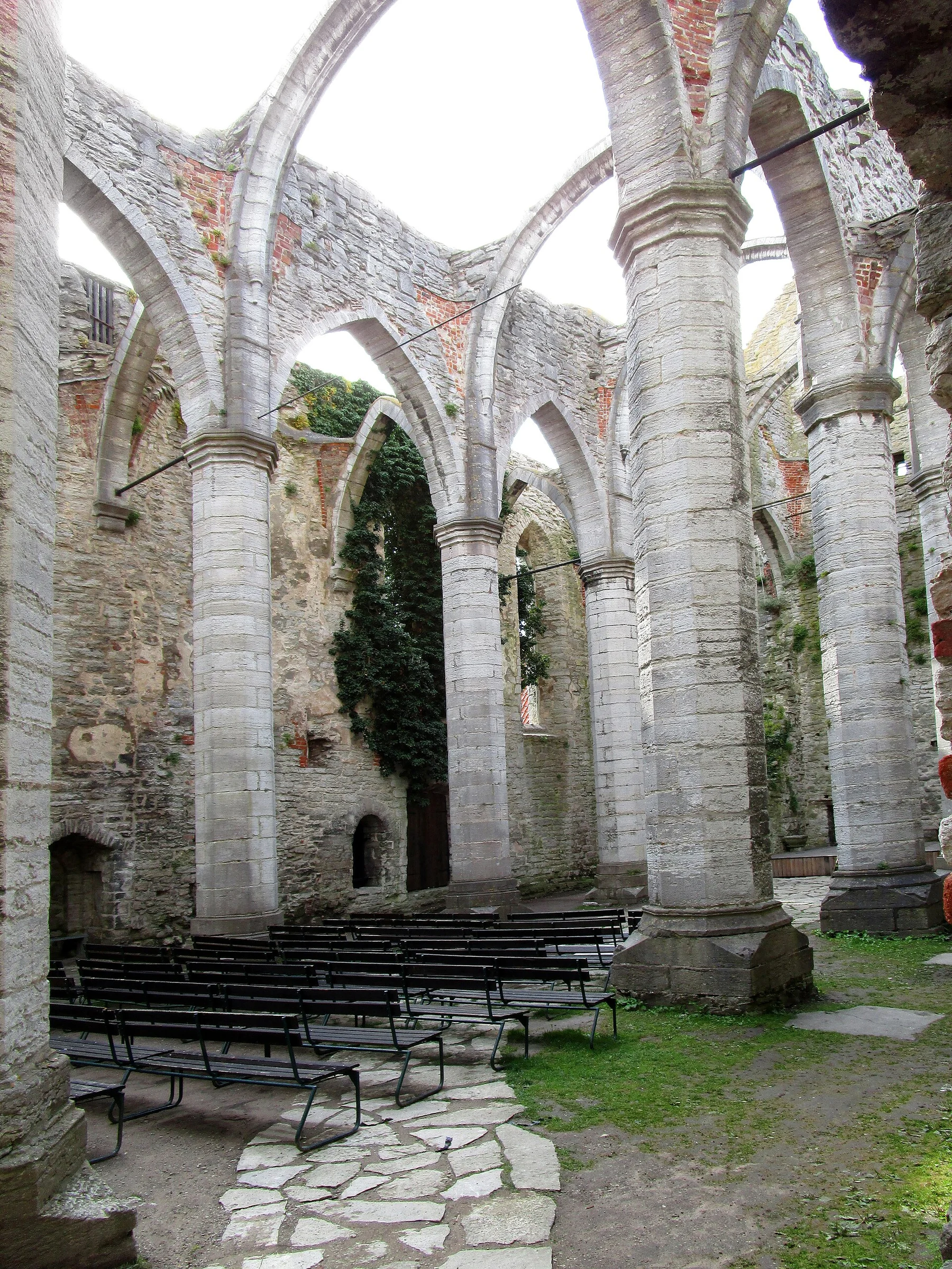 Innenraum der Ruine St. Karin in Visby mit Pfeilern, Spitzbögen und Bestuhlung unter freiem Himmel.