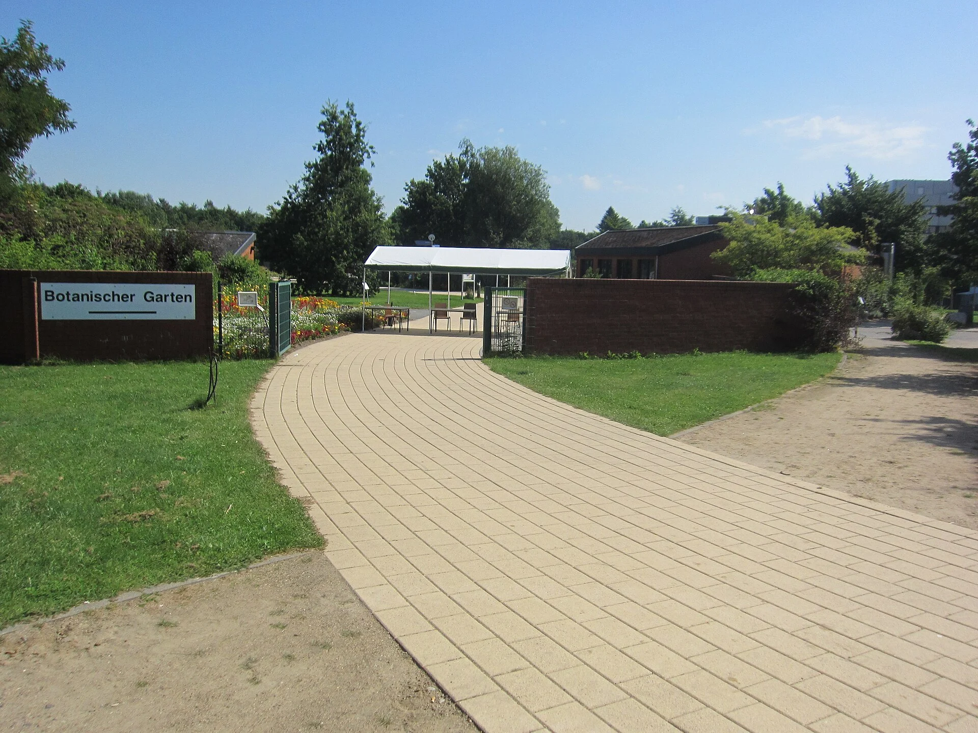Eingang mit Schild „Botanischer Garten" und gepflastertem Weg zum Botanischen Garten Kiel in Ravensberg.
