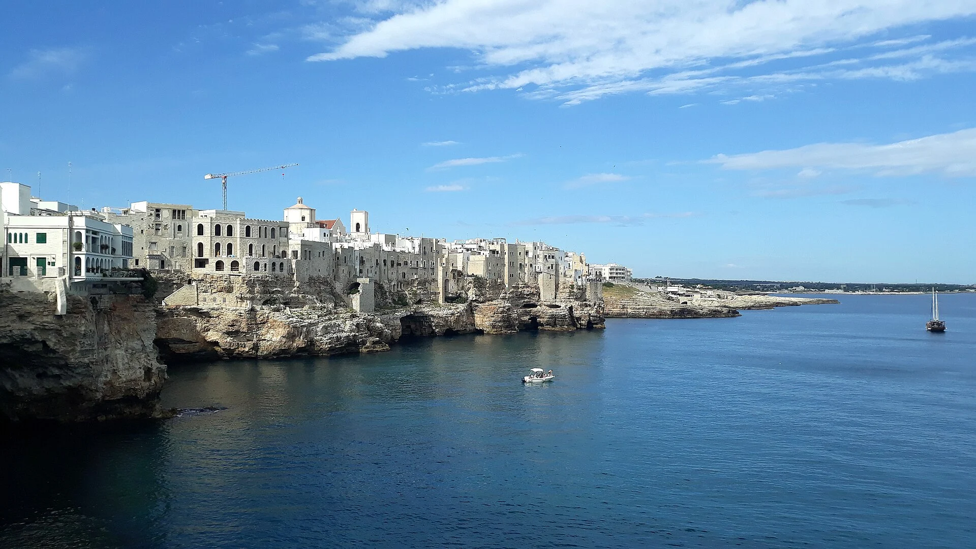 Panorama der Altstadt von Polignano a Mare auf den Kalkklippen an der Adria mit Booten im blauen Meer.
