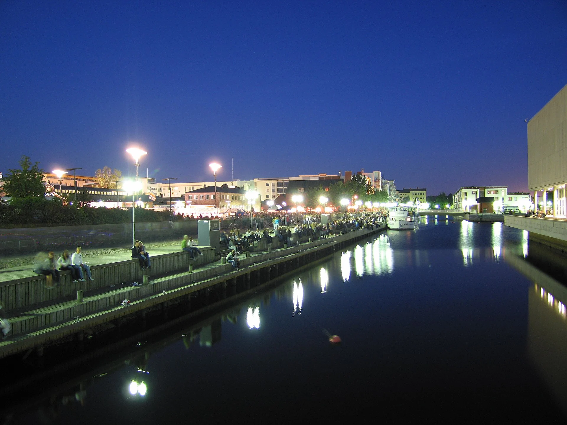 Die Uferzeile von Oulu am Abend, mit beleuchteten Gebäuden am Wasser