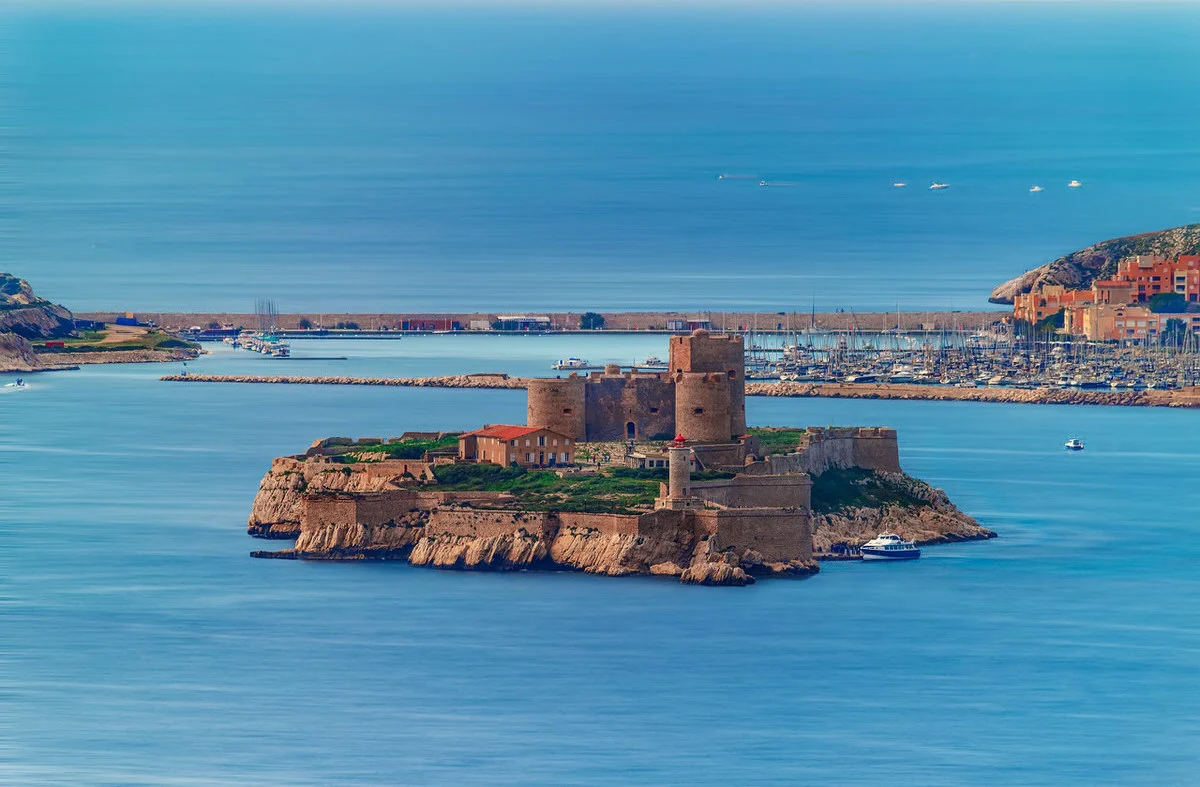 Die Festungsinsel Château d'If vor Marseille aus erhöhter Perspektive, dahinter Hafen und Küste.