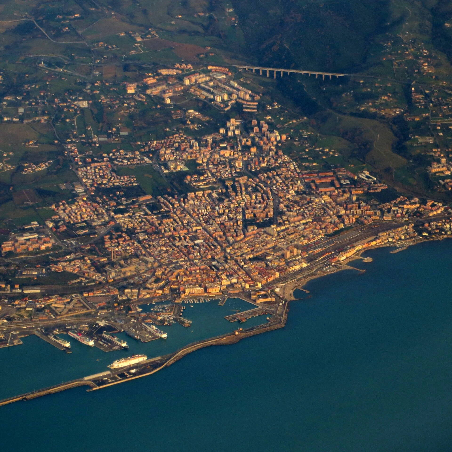 Luftbild von Civitavecchia mit Stadtgebiet, Hafenbecken und Kreuzfahrtpier an der tyrrhenischen Küste.