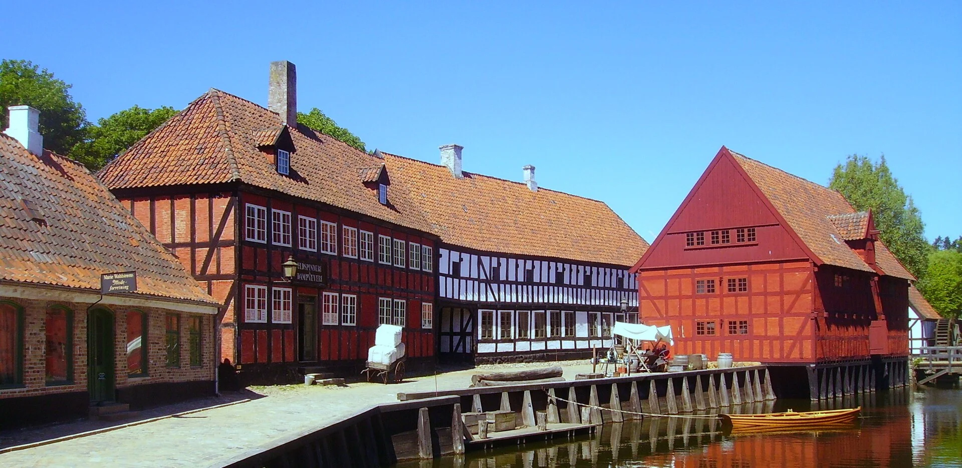 Rote Fachwerkhäuser am Wasserlauf im Freilichtmuseum Den Gamle By in Aarhus.
