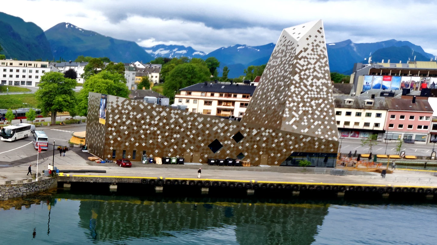 Das Norsk Tindesenter in Åndalsnes am Wasser, dahinter die Berge des Romsdals